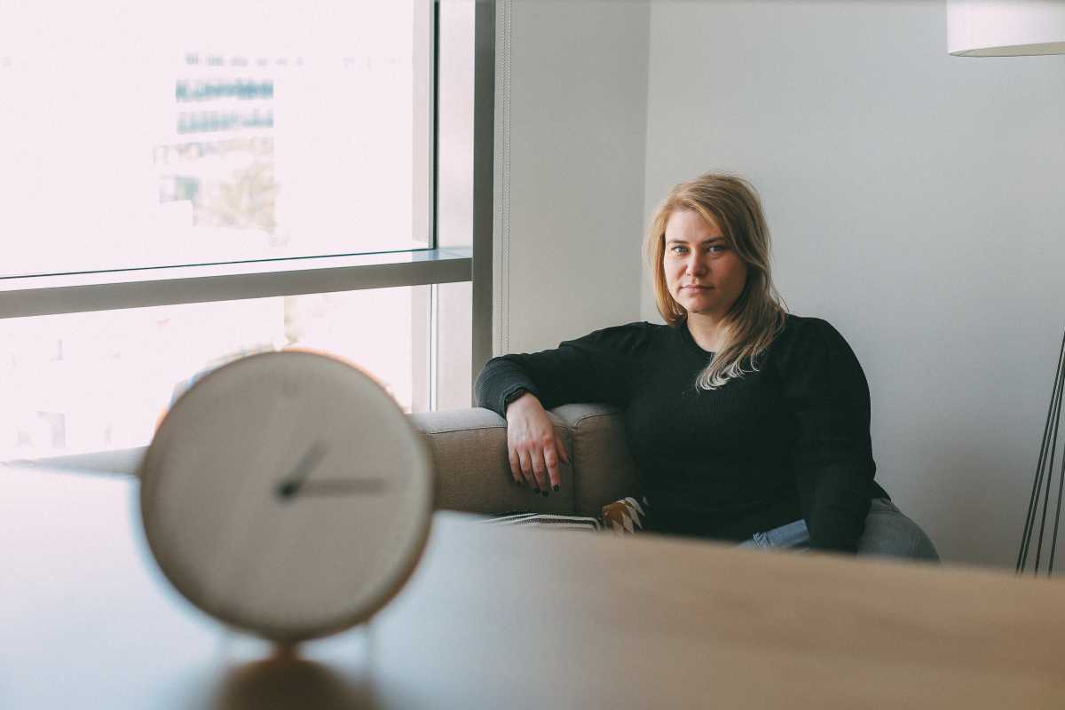 Woman sitting thoughtfully beside a window with a clock in the foreground, representing different experiences of time